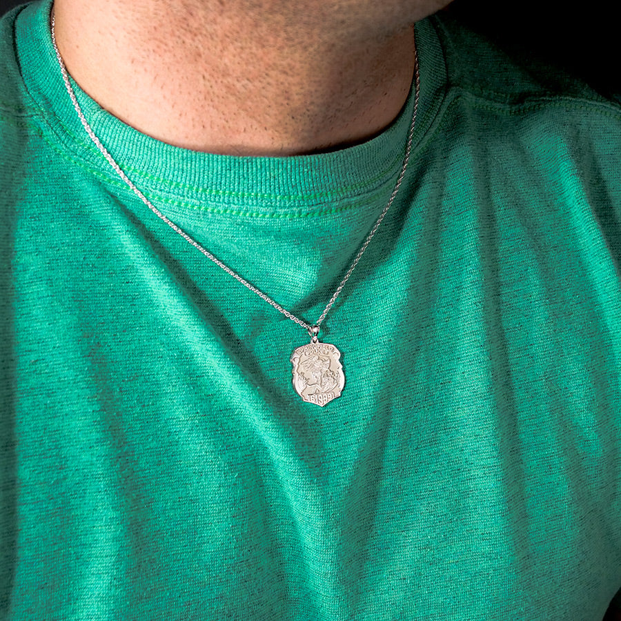 Lifestyle view of the Saint Michael police badge pendant on a teal top (PG88679, secondary photo 4)
