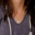 Lifestyle view of the Saint Michael police badge pendant on a gray top (PG88679, secondary photo 5)